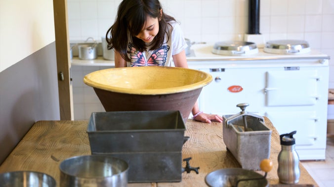 A child looks into a large bowl ion a table in the kitchen at Blickling Hall, Norfolk